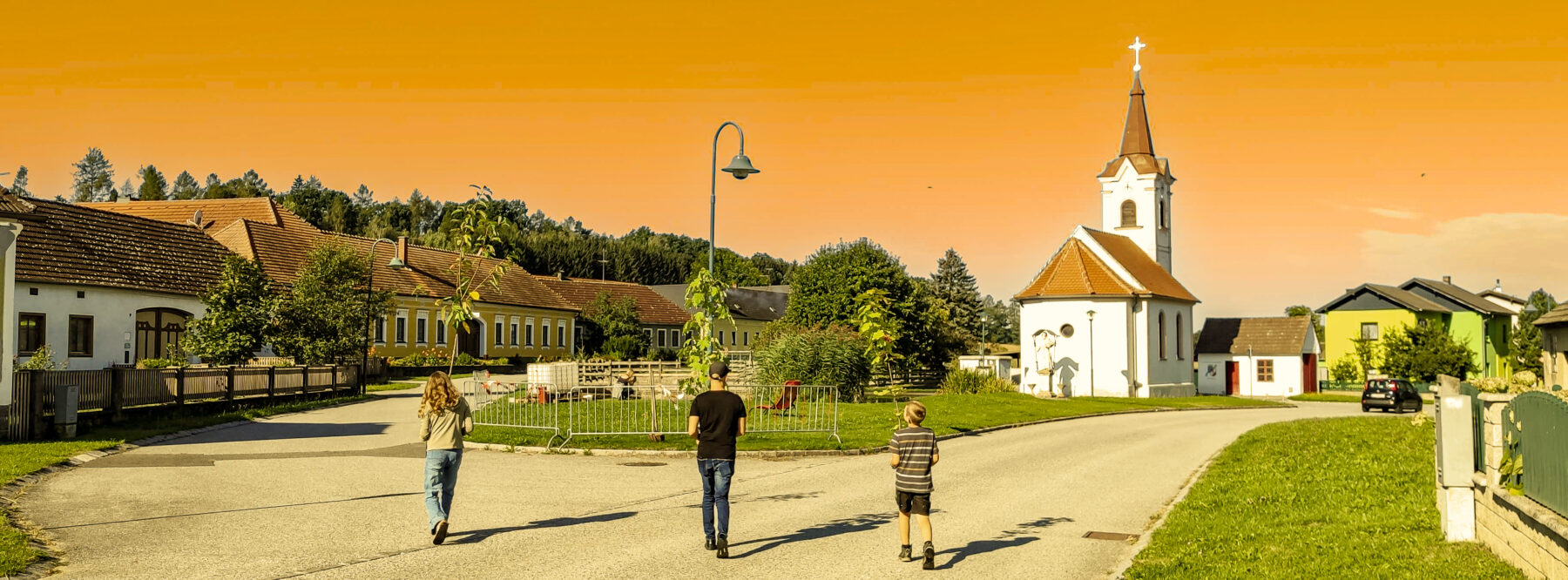 Außilahna und Hoamkema - Das Titelbild der Projektwebseite mit unserem Dorfplatz in Orange.