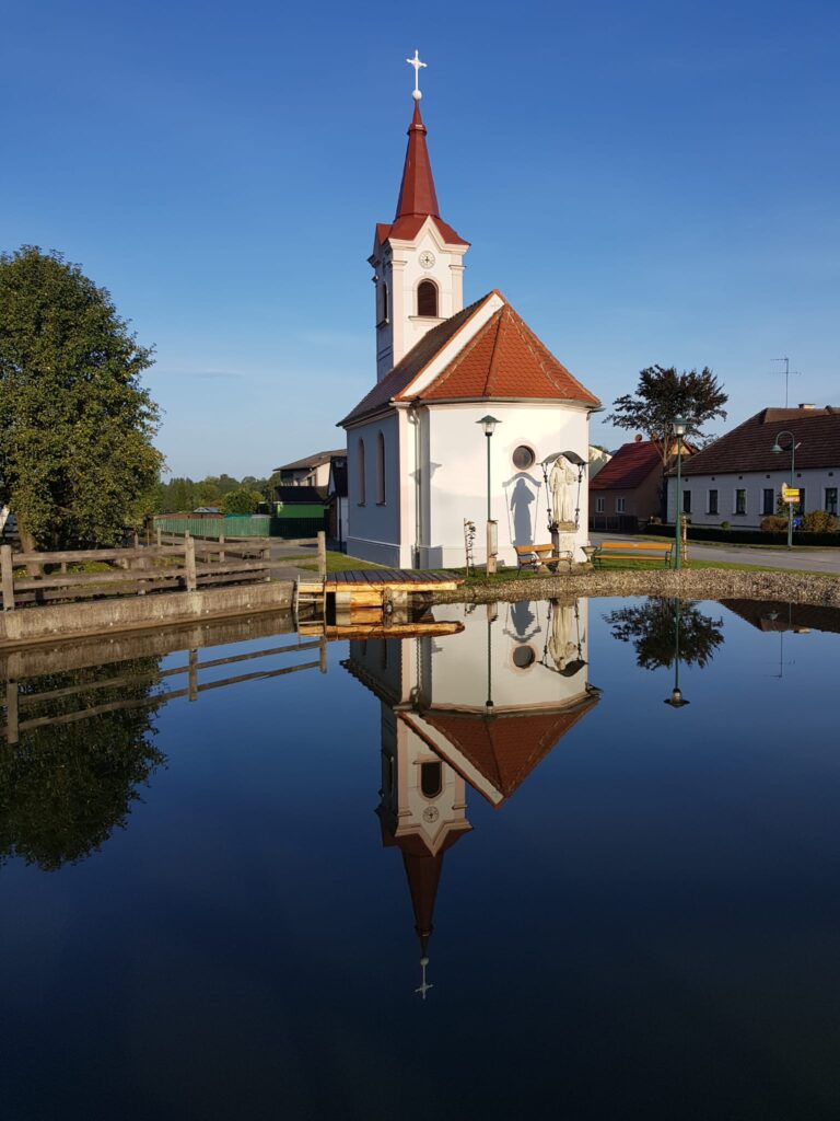 Kapelle Rafings mit unserem Löschteich im Vordergrund und einer perfekten Spiegelung.